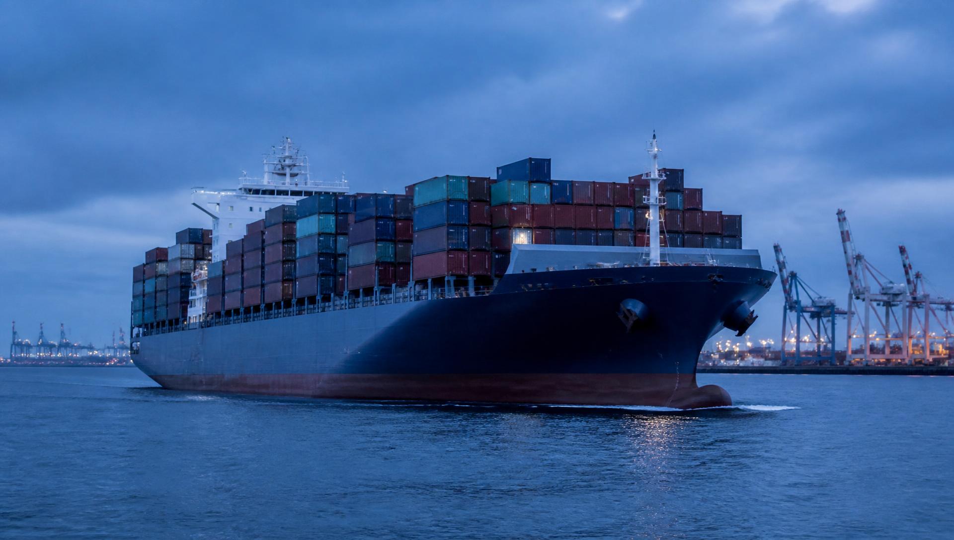 Containerschiff mit Containern vor einem Hafenterminal